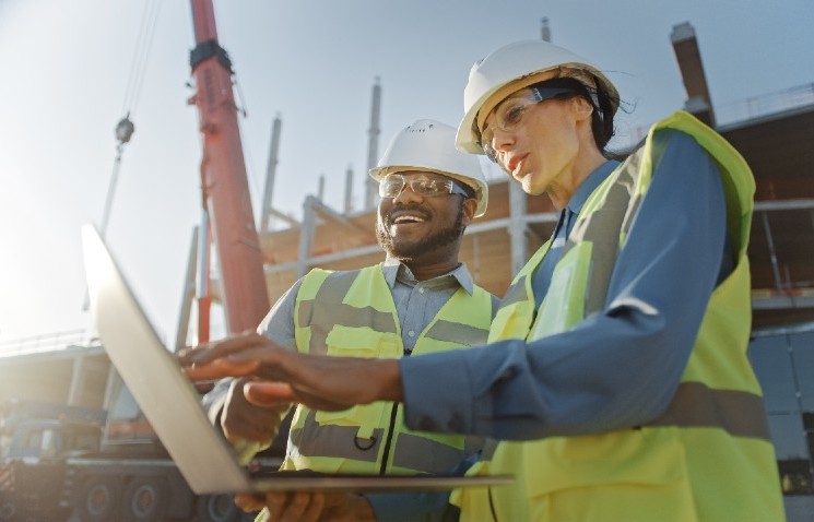 man and woman in hard hats and high vis jackets on a building site